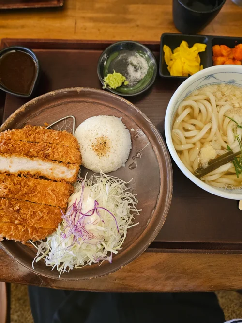 나무 트레이에 담긴 돈가스 정식과 우동, 밥과 반찬이 함께 세팅된 모습