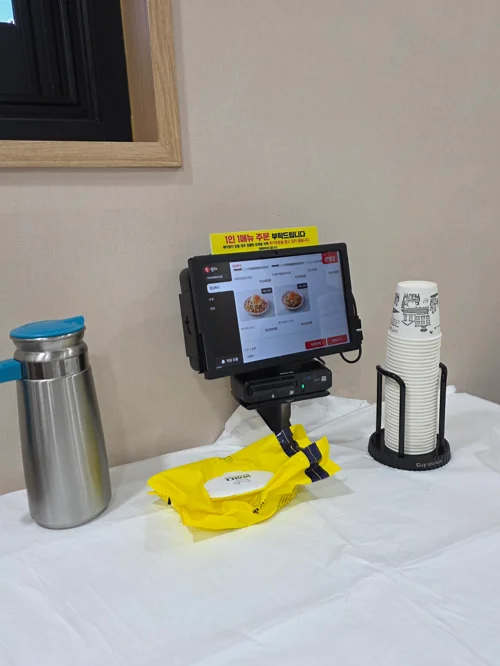 가보오토종닭 태블릿 주문기와 물통, 컵이 놓인 셀프 서비스 테이블