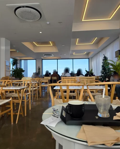 밝은 간접조명과 원목 테이블이 있는 모던한 카페 내부