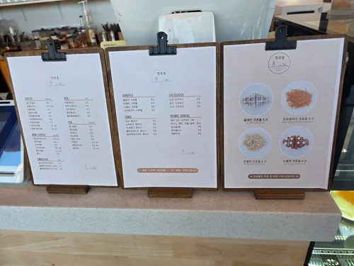 클립보드에 고정된 세 장의 카페 메뉴판이 카운터에 나란히 놓여있음