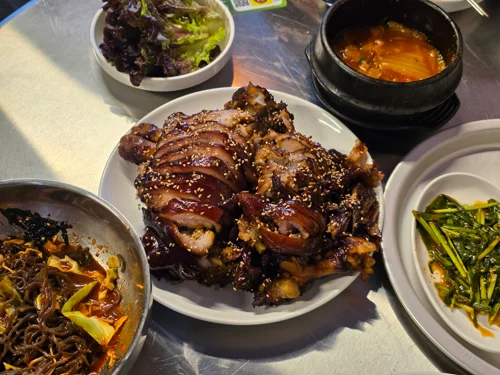 무등족발 메인 족발 한 접시, 통깨가 뿌려진 윤기 나는 족발과 김칫국 쌈채소 부추가 함께 놓여있다