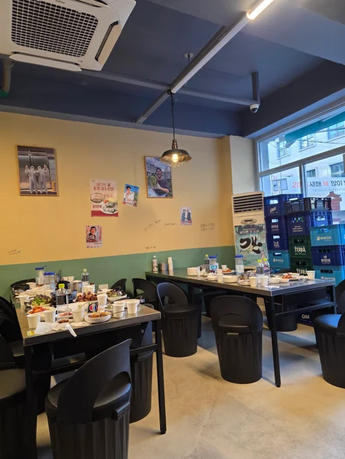 무등족발 매장 내부, 노란색과 녹색 벽면에 레트로 포스터가 붙어있고 검은색 테이블과 의자가 배치되어 있다
