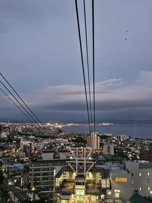 케이블카 케이블과 타워 너머로 보이는 해질녘 도시 전경과 바다