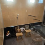 베이지색 타일 벽과 검은색 욕조가 있는 한국 전통 목욕탕 내부