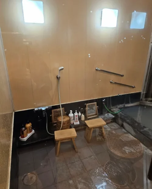 베이지색 타일 벽과 검은색 욕조가 있는 한국 전통 목욕탕 내부