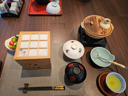 일본 료칸 조식 세팅 - 나무 격자 찬합, 옻칠 국그릇, 녹차, 도기 냄비가 놓인 테이블