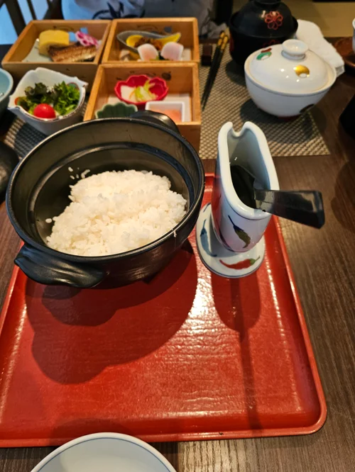 빨간 옻칠 쟁반 위 가마솥 밥과 간장병, 뒤편 나무 찬합에 담긴 반찬들