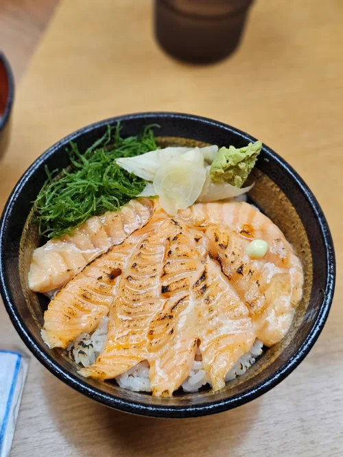 검은 그릇에 담긴 토치 연어 덮밥과 와사비, 절임 생강 토핑