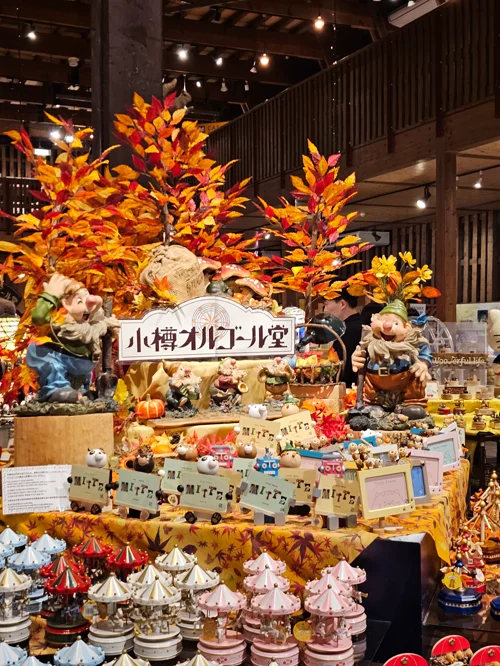 오타루 오르골당 내부에 가을 단풍 장식과 난쟁이 피규어, 회전목마 오르골이 진열된 모습