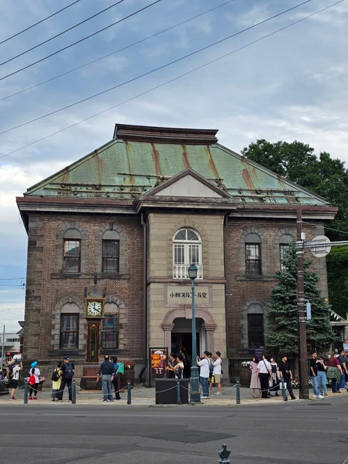 오타루 오르골당 벽돌 건물 외관과 입구 앞에 서 있는 관광객들