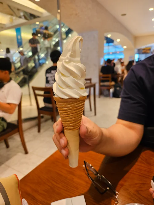 카페에서 손으로 든 소용돌이 모양의 하얀 소프트아이스크림 콘