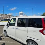 파란 하늘 아래 일본 주차장에 주차된 흰색 슬라이딩 도어 미니밴