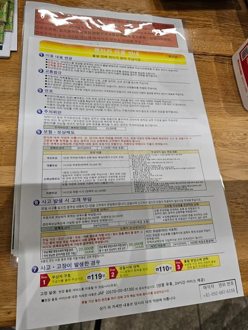 나무 테이블 위에 놓인 일본 렌터카 한국어 이용 안내 문서