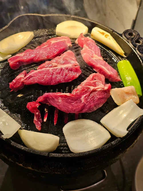 주물 원형 그릴 위에 생고기와 양파, 청양고추가 올려진 징기스칸 구이 모습