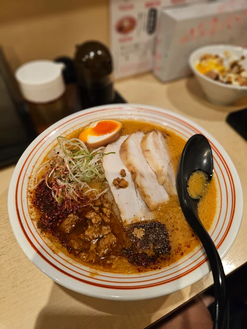 두꺼운 차슈와 반숙 달걀이 올려진 진한 주황빛 국물의 일본식 라멘