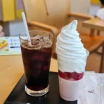 트레이 위에 아이스 아메리카노와 딸기 소프트아이스크림 파르페가 놓인 카페 테이블