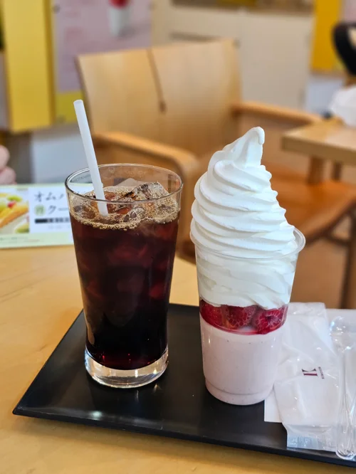 트레이 위에 아이스 아메리카노와 딸기 소프트아이스크림 파르페가 놓인 카페 테이블