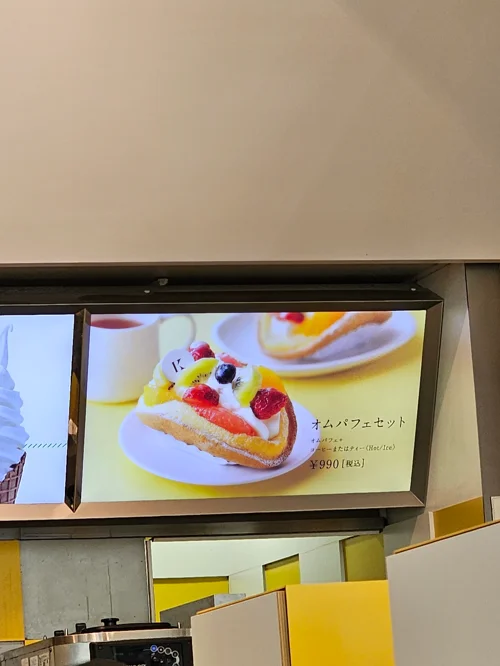 일본 카페 카운터 위 디지털 메뉴판에 과일 오무파페 세트 990엔이 표시된 모습