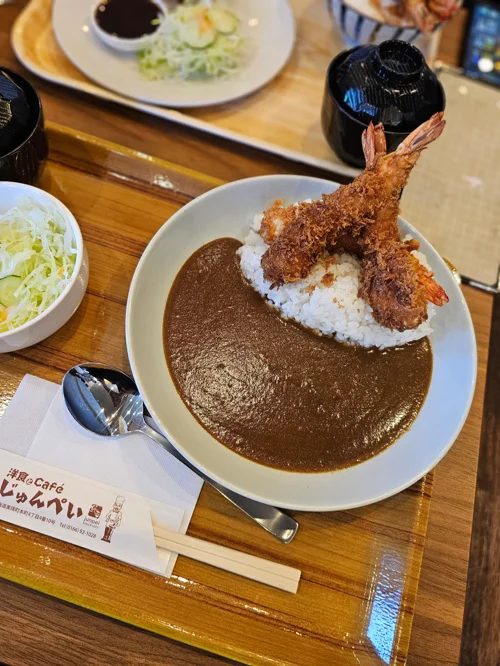 나무 트레이 위에 에비카츠 두 마리가 올라간 일본식 카레라이스와 양배추 샐러드 정식