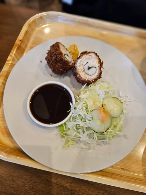 나무 트레이 위 치킨롤 카츠와 양배추 샐러드 소스