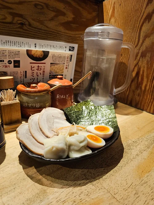 검은 접시에 차슈, 반숙 달걀, 김이 담긴 쓰케멘 토핑 세트