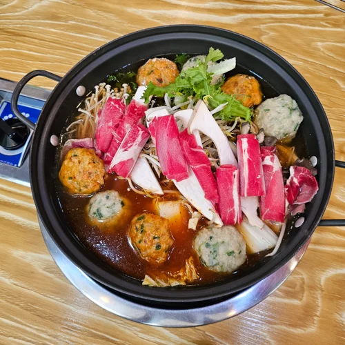 붉은 마라 육수에 소고기와 각종 완자, 버섯이 담긴 훠궈 냄비