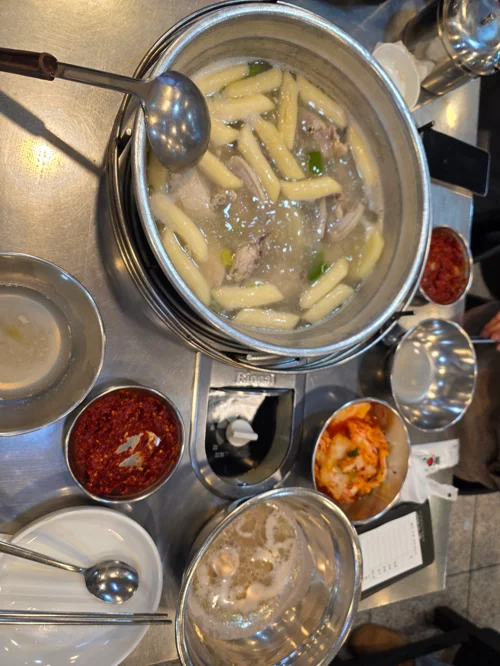 스테인리스 냄비에 담긴 뼈해장국과 각종 반찬이 차려진 한식 식탁