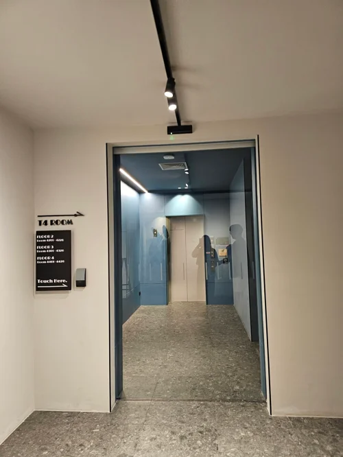 T4 ROOM 안내판이 있는 건물 내부 복도 입구와 열린 유리문
