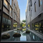 두 현대식 건물 사이 자연석이 놓인 잔잔한 수공간과 반영