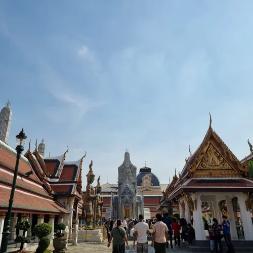 방콕 왕궁 경내에 늘어선 금빛 장식의 태국 전통 사원 건물들과 관광객들