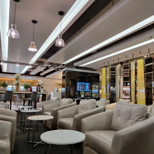 크림색 소파와 펜던트 조명이 있는 고급스러운 공항 비즈니스 라운지 내부