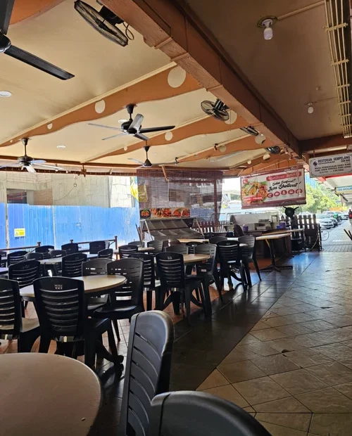 천장 선풍기와 검정 의자가 줄지어 있는 동남아 오픈형 로컬 레스토랑 내부