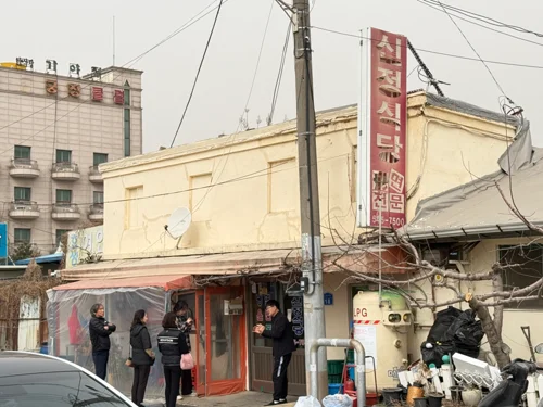 오래된 노란 외벽 건물에 빨간 간판이 달린 한국 동네 식당 외관