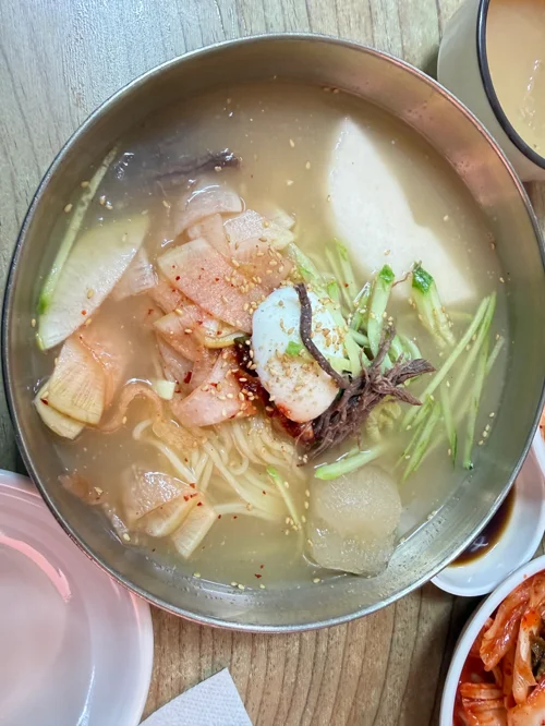 스테인리스 대접에 담긴 맑은 육수의 한국식 냉면