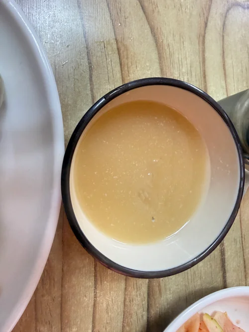 나무 테이블 위 검은 테두리 그릇에 담긴 참깨 소스