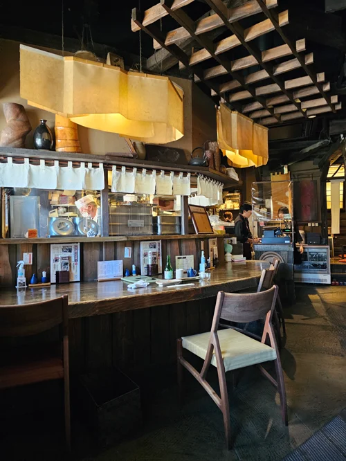 어두운 목재와 종이 조명으로 꾸며진 일본 전통 이자카야 카운터석 내부